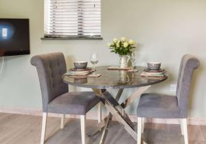a dining room table with two chairs and a vase of flowers at Pentarow Barn in Falmouth