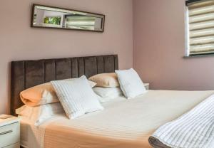 a bed with white pillows and a mirror on the wall at Pentarow Barn in Falmouth +7 photos