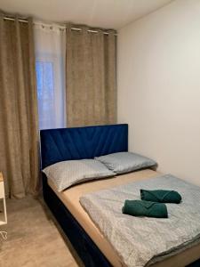a bed with a blue headboard and two green pillows on it at Apartament Tarasy Wenecji 2 in Gniezno