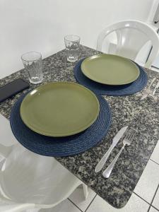 a table with two green plates and silverware on it at Aparthotel holandeses in São Luís