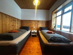 two beds in a room with wooden walls and windows at Hengifosslodge Skáldahús in Egilsstaðir