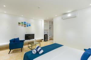 a bedroom with a bed and a chair and a television at Villa Santorini Boutique & Hotel in Pirenópolis