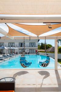 a large swimming pool with chairs and umbrellas at Villa Santorini Boutique & Hotel in Pirenópolis