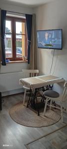 a living room with a table and a tv on the wall at Garsonka u pivovaru, centrum Rožnov in Rožnov pod Radhoštěm