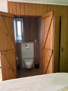 ein Badezimmer mit Toilette und Holztür in der Unterkunft B&B de Danser in Klaaswaal