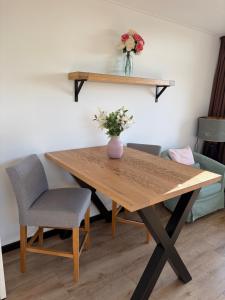 ein Holztisch mit einer Blumenvase darauf in der Unterkunft B&B de Danser in Klaaswaal
