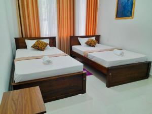 two twin beds in a room with a table at Kandy Rainbow Villa in Kandy