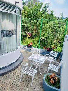 a patio with two white chairs and a table at Kandy Rainbow Villa in Kandy