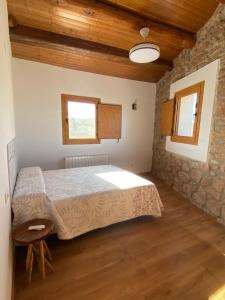 a bedroom with a bed and a stone wall at Cal Perico in San Pedro Sallavinera