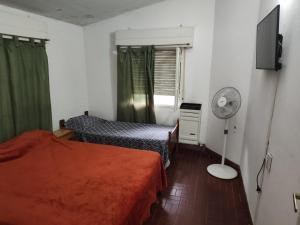 a small room with two beds and a fan at Casa Centrica 5 Huésped in Pinamar