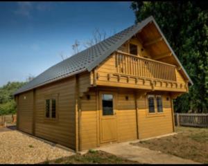 a large wooden cabin with a balcony and a deck at Buzzards Retreat in Larling