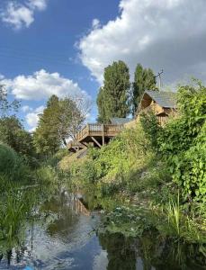 a wooden bridge over a river with a house at Buzzards Retreat in Larling