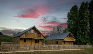 two wooden houses with a fence and a cloudy sky at Buzzards Retreat in Larling +5 photos