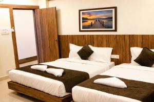 a hotel room with two beds with pillows on them at Hotel Sakura Inn in Hosūr