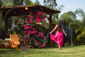 a woman in a pink dress walking through a garden at Pousada Viver Capitólio in Capitólio