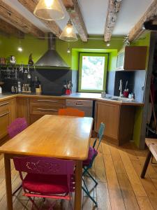 a kitchen with a wooden table and colorful chairs at La Maison du Patou in Cadéac
