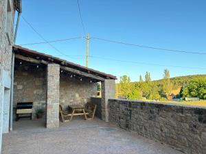 a patio with a table and a stone wall at Dúplex les Coromines in San Pedro Sallavinera