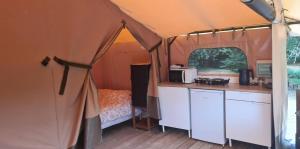 a tent with a kitchen and a microwave in it at Tente lodge la perche in Le Lonzac