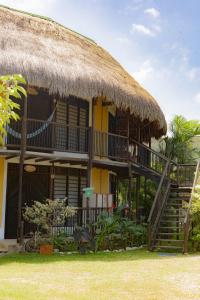 a house with a thatched roof and stairs and chairs at Hostal El Bohío in Palomino