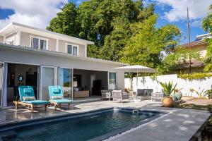 a house with a swimming pool with two chairs and an umbrella at Villa Pwani in Baie du Tombeau
