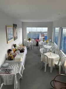 a dining room with white tables and chairs and windows at Pousada coração da serra in Serra de São Bento