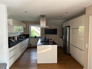 a large kitchen with white cabinets and a sink at Gemütliche Wohnung in Baldham bei München in Vaterstetten