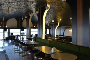 a restaurant with tables and chairs and a bar at Palm Garden in Korucuk