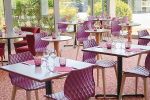 a row of tables in a restaurant with purple chairs at Brit Hotel Nantes Vigneux - L'Atlantel in Vigneux-de-Bretagne +51 photos