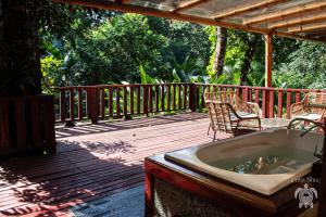 a wooden deck with a tub and chairs on it at Casa Shec- An Oceanfront Jungle Retreat in Drake