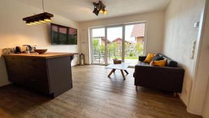 a living room with a couch and a kitchen at Ferienwohnung Wiesenweg - Aktiv im Allgäu in Seeg