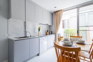 a kitchen with white cabinets and a table with chairs at SPACIOUS AND BRIGHT 2BR TownHouse7 MonkeyHill in Ban Sam Kong