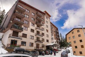a tall building with cars parked in a parking lot at Apartman Bn Vlasic in Vlasic