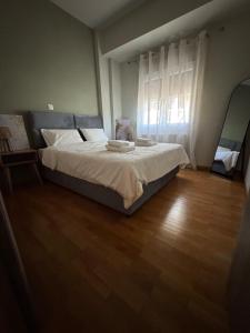 a bedroom with a bed with white sheets and a wooden floor at Comfortable Family Apartment P3 in Larisa