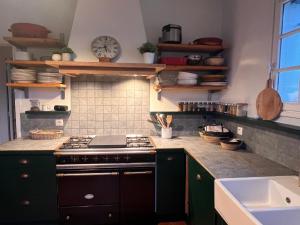 a kitchen with a stove and a clock on the wall at Maison OHANZIA Villefranque in Villefranque