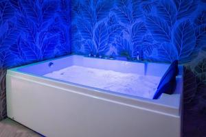 a bath tub in a bathroom with blue wallpaper at Corte Atenea Guest House Experience & Spa in Agrigento +59 photos
