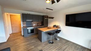 a kitchen with a counter with stools and a television at Ferienwohnung Wiesenweg - Aktiv im Allgäu in Seeg