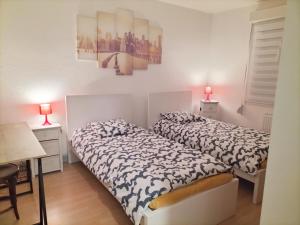 two beds in a small room with two lamps at Nidou in Sochaux