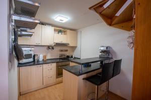 a kitchen with wooden cabinets and a black counter top at Lara Mezonet Tatry in Veľká Lomnica