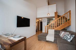 a living room with a couch and a tv at Lara Mezonet Tatry in Veľká Lomnica