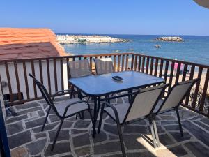a blue table and chairs on a balcony with the ocean at Dafnis beach house in Karavostamo +15 photos