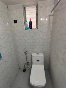 a white bathroom with a toilet and a window at Shraddha's Guest House in Kolhapur