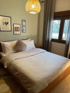 a bedroom with a bed with white sheets and a chandelier at Loui's Garden House in Thessaloniki