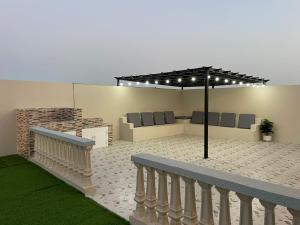 a patio with a bench and an umbrella at شالية مزايا الاشخرة in Al Sharqiyah