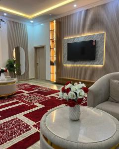 a living room with a television and a vase of flowers at شالية مزايا الاشخرة in Al Sharqiyah