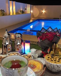 a table with bowls of food and a swimming pool at شالية مزايا الاشخرة in Al Sharqiyah