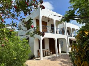 a white building with a balcony on top of it at Kameleon Blue Arts Lodge in Kizimkazi