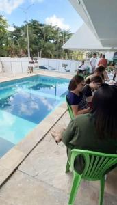 a group of people sitting in chairs by a swimming pool at CASAMAR Olinda in Olinda