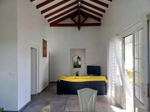 a bedroom with a bed with a yellow blanket at Flamboyant in Sainte-Anne