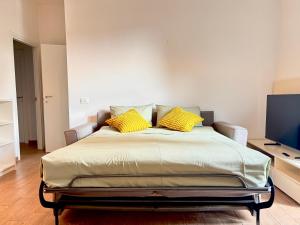 a bedroom with a bed with yellow pillows on it at BorgoLuce Spacious Apt - FREE Parking - Near Airport & Center in Bergamo +18 photos