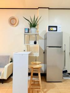 a kitchen with a white refrigerator and a stool at Casita del Mabini - Homestay in Mabini